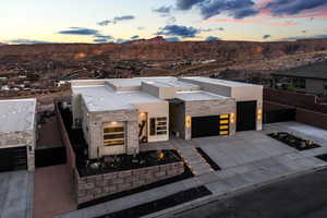 Contemporary house featuring stucco siding, concrete driveway, a mountain view, a garage, and stone siding