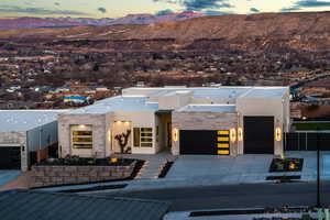 Contemporary house with an attached garage, a mountain view, stone siding, concrete driveway, and stucco siding