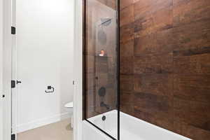 Full bath with toilet, shower / bath combination with glass door, and baseboards