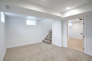 Below grade area with recessed lighting, visible vents, stairway, carpet flooring, and baseboards