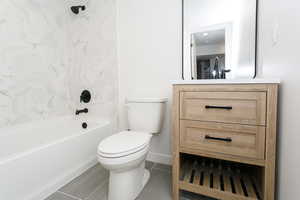 Bathroom featuring toilet, washtub / shower combination, vanity, and baseboards