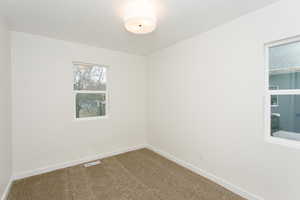 Carpeted spare room with visible vents and baseboards