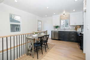 Kitchen featuring tasteful backsplash, light wood-style flooring, electric range, stainless steel dishwasher, and white cabinetry