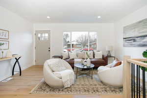 Living area with light wood-style flooring, visible vents, baseboards, and recessed lighting