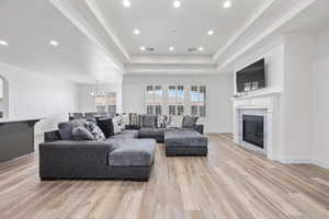 Living room featuring a glass covered fireplace, light wood-style flooring, and baseboards