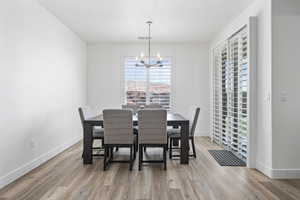 Dining area featuring a chandelier, visible vents, baseboards, and wood finished floors