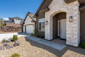 Doorway to property featuring stone siding, an attached garage, and stucco siding