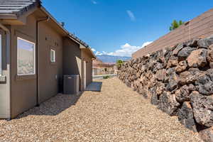 View of property exterior with a tile roof, stucco siding, central AC unit, a mountain view, and fence