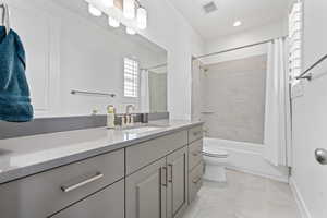 Bathroom featuring baseboards, visible vents, toilet, shower / bath combination with curtain, and vanity