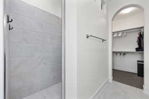 Bathroom with a spacious closet, baseboards, and a tile shower