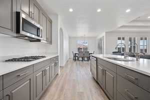 Kitchen featuring appliances with stainless steel finishes, light wood-type flooring, a sink, and gray cabinetry