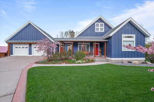 View of front of house with board and batten siding, a porch, driveway, and a front yard