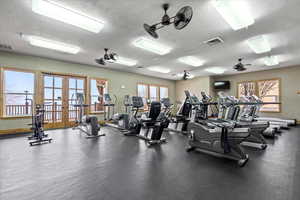Gym featuring a healthy amount of sunlight, visible vents, a textured ceiling, and french doors