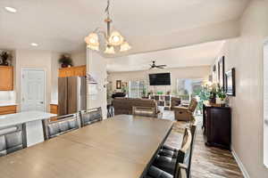 Dining space featuring ceiling fan with notable chandelier, recessed lighting, wood finished floors, and baseboards