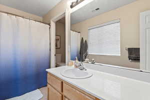 Bathroom featuring visible vents, vanity, toilet, and a textured ceiling