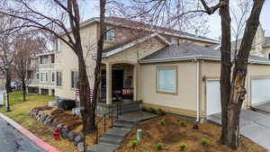 View of front of property with a garage, driveway, roof with shingles, and stucco siding