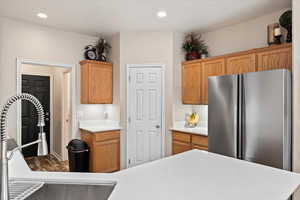 Kitchen with light countertops, a sink, freestanding refrigerator, and recessed lighting