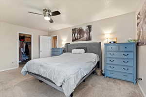 Bedroom featuring light carpet, baseboards, a walk in closet, and a closet