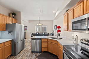 Kitchen with stainless steel appliances, a peninsula, a sink, and light countertops