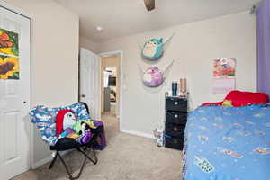 Carpeted bedroom featuring ceiling fan and baseboards