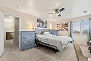 Bedroom featuring light carpet, a textured ceiling, visible vents, and a ceiling fan