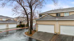 Exterior space with a garage, stucco siding, and roof with shingles