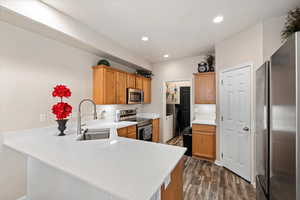 Kitchen featuring a peninsula, stainless steel appliances, light countertops, washing machine and dryer, and a sink