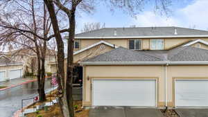 View of front of property with driveway, a shingled roof, a garage, and stucco siding