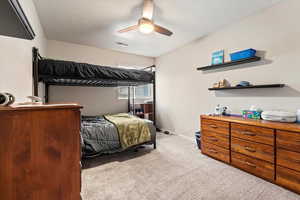 Carpeted bedroom featuring baseboards, ceiling fan, visible vents, and a textured ceiling