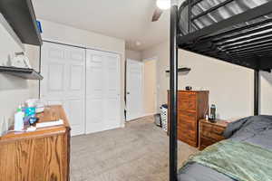 Bedroom featuring a ceiling fan, a closet, and carpet flooring
