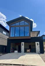 Modern Mountain house with an attached garage, driveway, and stone siding Like render shown.