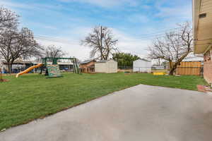 View of yard featuring a playground, a patio, a shed, a fenced backyard, and an outdoor structure