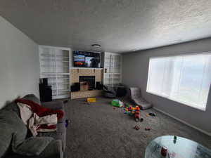 Living room featuring carpet, a fireplace, visible vents, and a textured ceiling