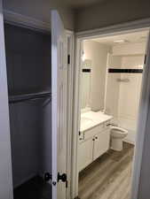 Bathroom featuring shower / washtub combination, vanity, toilet, and wood finished floors