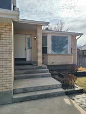 Doorway to property featuring fence and brick siding