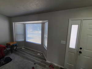 Entryway featuring baseboards, a textured ceiling, visible vents, and wood finished floors