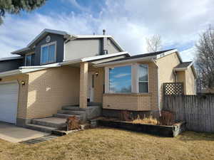 View of front of house featuring a garage, a front yard, brick siding, and fence