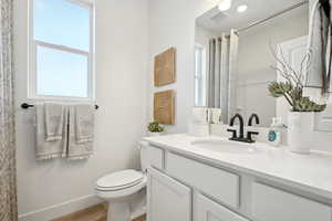Bathroom with a wealth of natural light, vanity, toilet, and wood finished floors