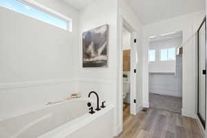 Full bath featuring a wealth of natural light, a bath, toilet, and wood finished floors