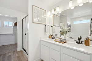 Bathroom with a sink, visible vents, a stall shower, and wood finished floors