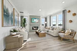 Living room featuring recessed lighting, a fireplace, visible vents, and light wood-style flooring
