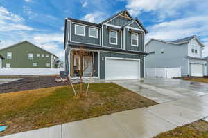 View of front of home with a garage, fence, concrete driveway, board and batten siding, and a front yard