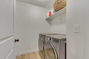 Laundry room with laundry area, light wood-type flooring, independent washer and dryer, and baseboards