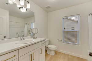Full bathroom with toilet, visible vents, wood finished floors, and vanity