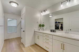Full bathroom featuring double vanity, baseboards, a sink, and wood finished floors