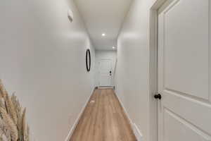 Hallway with light wood finished floors, recessed lighting, visible vents, and baseboards
