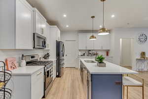 Kitchen with stainless steel appliances, light countertops, a center island with sink, and a kitchen breakfast bar