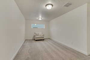 Unfurnished room with light carpet, visible vents, and a textured ceiling