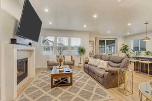 Living room featuring light wood-style floors, a glass covered fireplace, baseboards, and recessed lighting