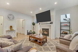 Living area featuring recessed lighting, a glass covered fireplace, light wood-style flooring, and baseboards
